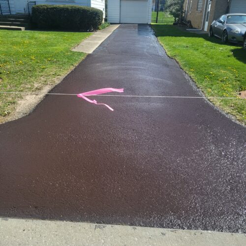 Newly paved driveway with pink ribbon.