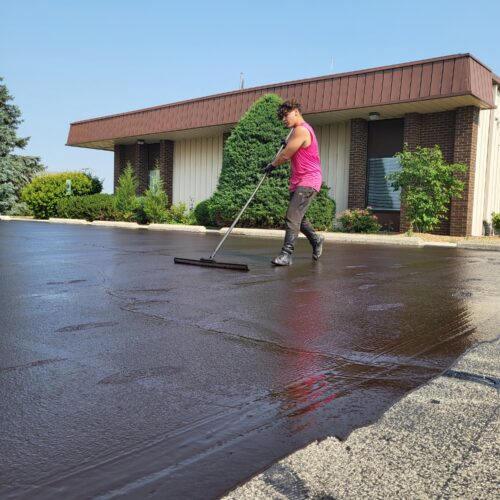Man spreading sealant on a parking lot.