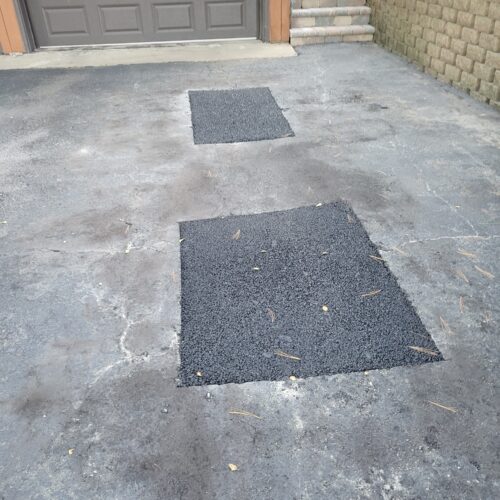 Asphalt patches on driveway surface.